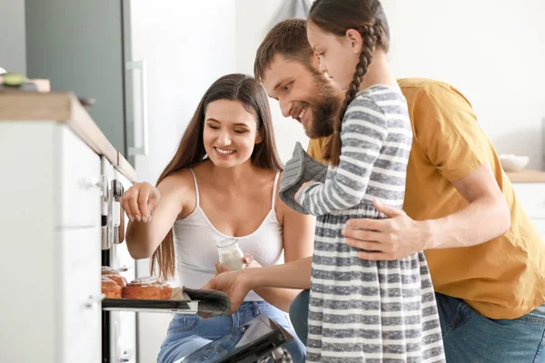 Young family with freshly baked buns in kitchen — Stock Photo, Image
