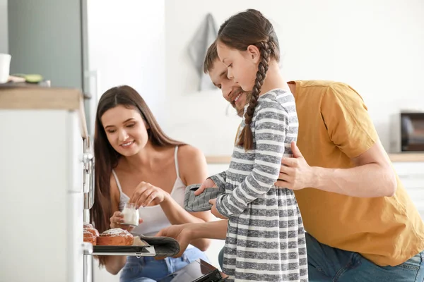 Young family with freshly baked buns in kitchen — Stock Photo, Image