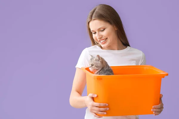 Beautiful young woman holding box with cute cat on color background — Stock Photo, Image