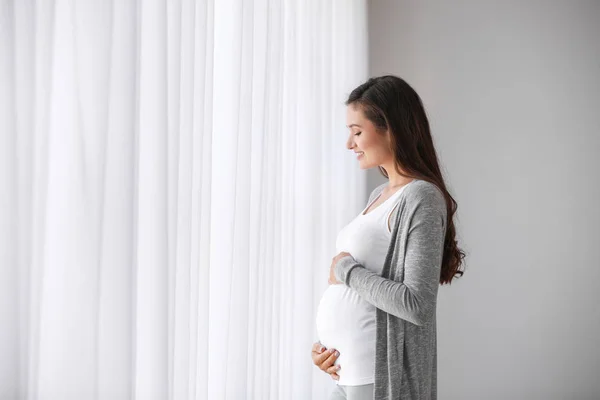 창문 근처에 임신 한 젊은 여자 — 스톡 사진