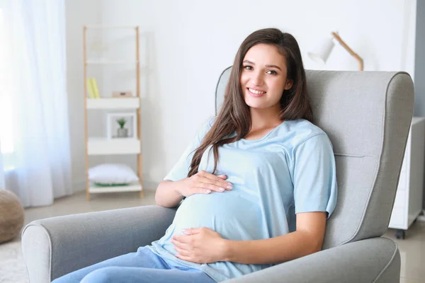 Mladá těhotná žena sedí v křesle u vás doma — Stock fotografie