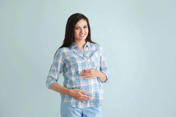 Mladá těhotná žena na barevném pozadí — Stock fotografie