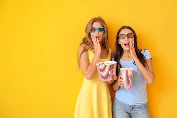 Women with popcorn watching horror movie on color background — Stock Photo, Image