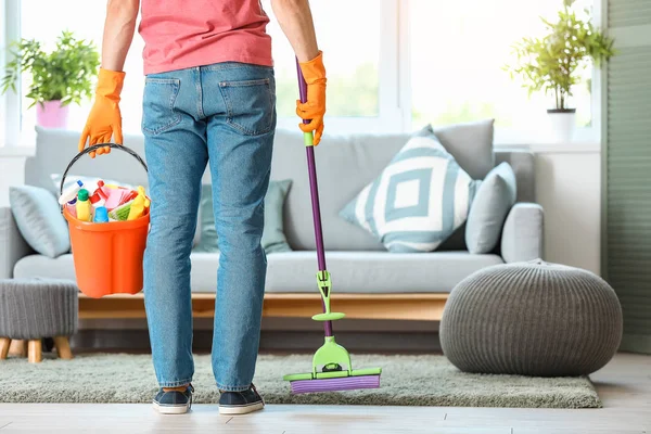 Junger Mann mit Putzmitteln im Zimmer — Stockfoto