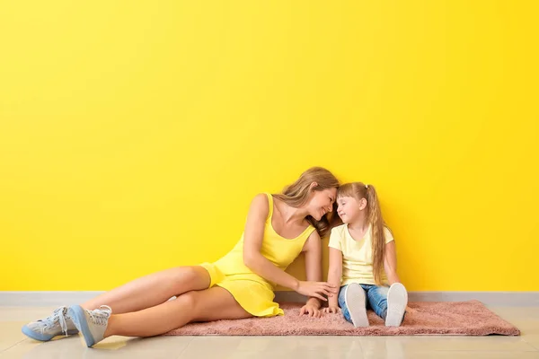 컬러 벽 근처 바닥에 앉아 딸과 함께 행복한 어머니의 초상화 — 스톡 사진