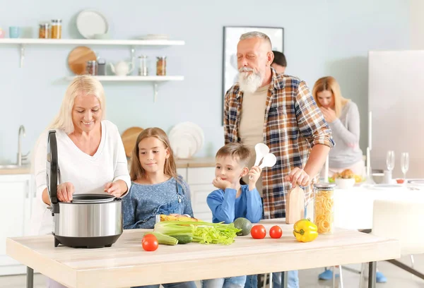 Бабушка и дедушка и маленькие дети с помощью современной мульти-плита на кухне — стоковое фото