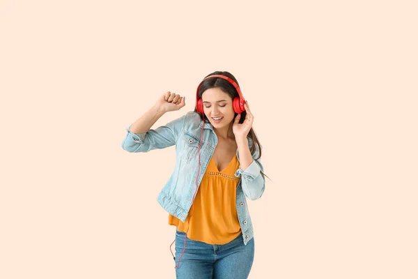Junge Frau mit Kopfhörern tanzt vor hellem Hintergrund — Stockfoto