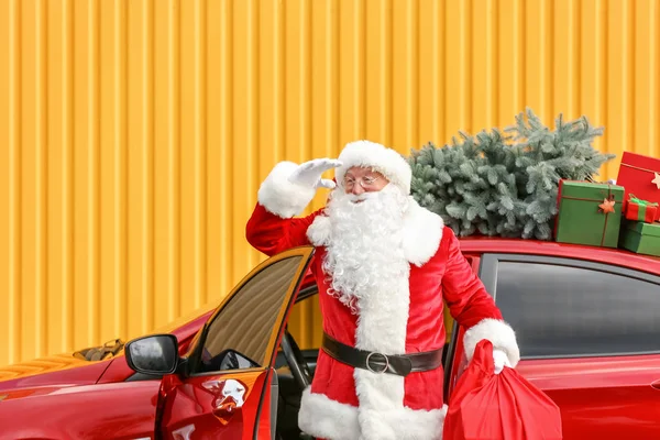 Papai Noel com presentes no saco olhando para longe perto do carro ao ar livre — Fotografia de Stock