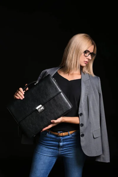 Beautiful stylish businesswoman with briefcase on dark background
