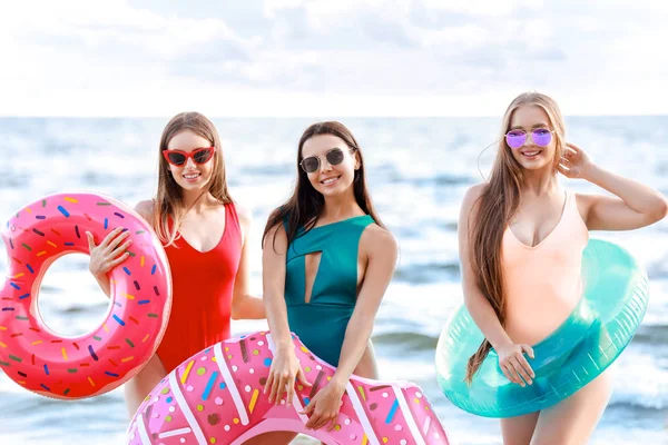 Jovens mulheres bonitas com anéis de natação na praia do mar no resort — Fotografia de Stock