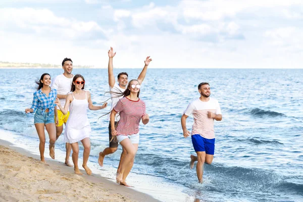 Heureux amis courir sur la plage de la mer à la station — Photo
