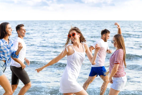 Happy friends running on sea beach at resort — Stock Photo, Image