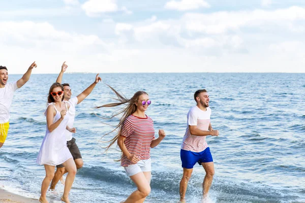 Happy friends running on sea beach at resort — Stock Photo, Image