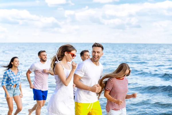 Amigos felices corriendo en la playa del mar en el resort — Foto de Stock