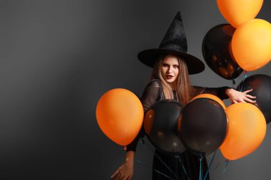 Gri arka planda Cadılar Bayramı için cadı gibi giyinmiş güzel kadın