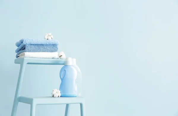 Stand with clean towels and washing agents near color wall — Stock Photo, Image