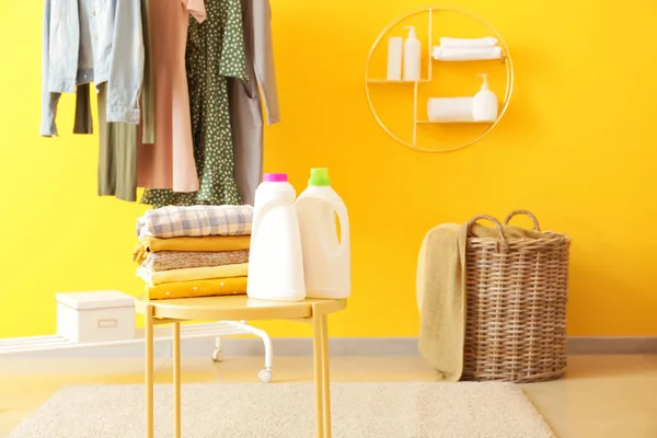 Bastidor con ropa, lavandería y agentes de lavado en la mesa en la habitación — Foto de Stock