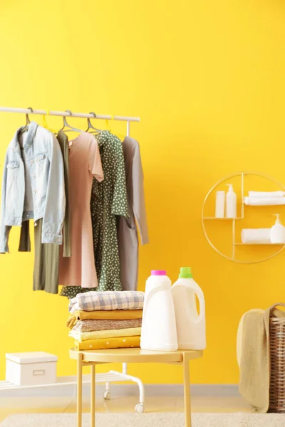 Bastidor con ropa, lavandería y agentes de lavado en la mesa en la habitación — Foto de Stock