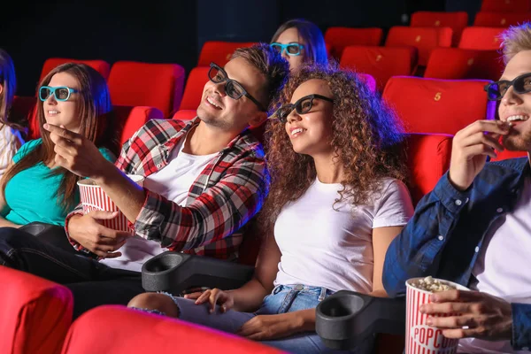 Friends with popcorn watching movie in cinema