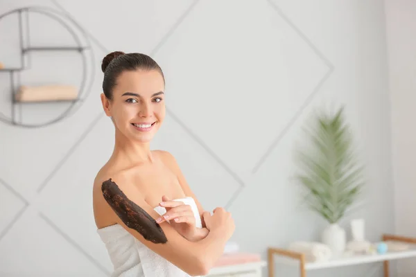 Hermosa mujer joven aplicando exfoliante corporal en casa — Foto de Stock