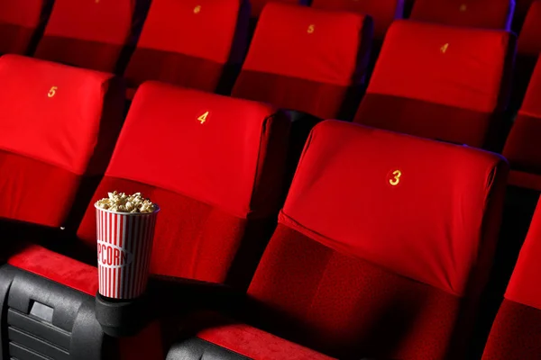 Copa de palomitas de maíz en la silla en el cine vacío — Foto de Stock