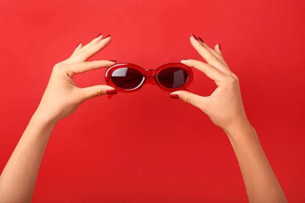 Руки женщины в стильных солнцезащитных очках на цветном фоне — стоковое фото