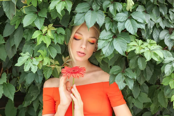 Beautiful young woman with gerbera flower outdoors — Stock Photo, Image