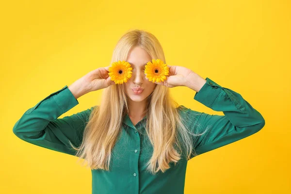 Grappige jonge vrouw met Gerbera bloemen op kleur achtergrond — Stockfoto