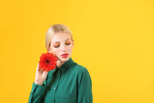 Hermosa mujer joven con flor de gerberas sobre fondo de color — Foto de Stock