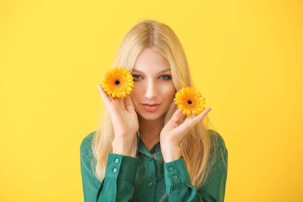 Vacker ung kvinna med Gerbera blommor på färg bakgrund — Stockfoto