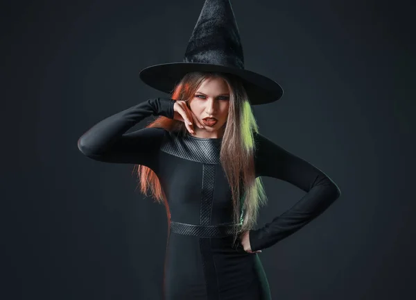 Krásná žena oblečená jako čarodějnice na Halloween na tmavém pozadí — Stock fotografie