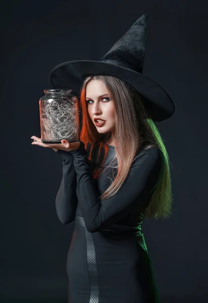 Mooie vrouw verkleed als heks voor Halloween op donkere achtergrond — Stockfoto