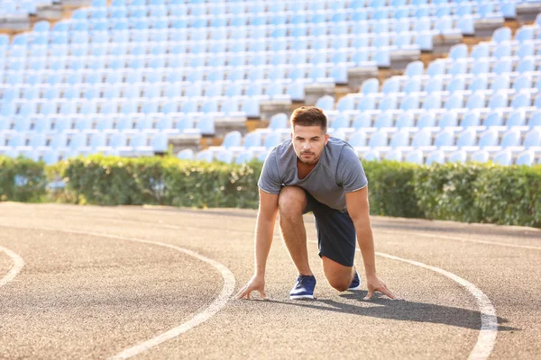 Sporty man in crouch start position at the stadium — Stock Photo, Image