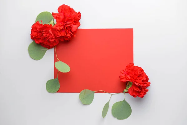 Beautiful carnation flowers and blank card on light background — Stock Photo, Image