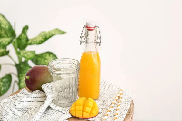 Bottle of tasty mango juice and glass on table