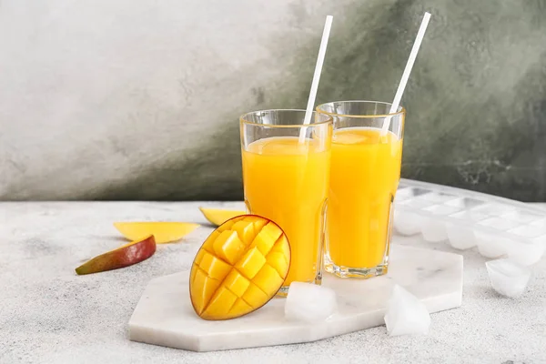Glasses of tasty mango juice on table
