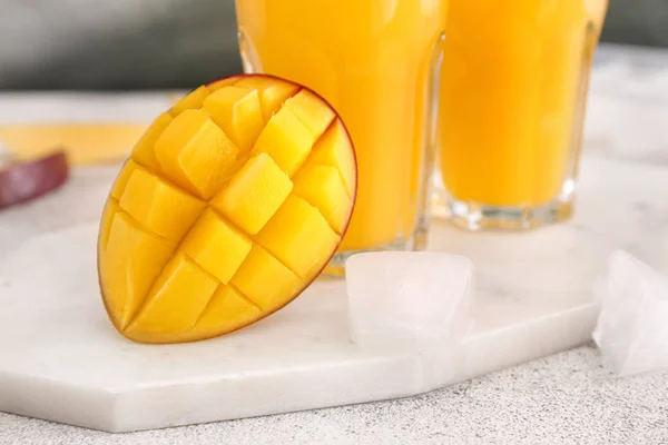 Tasty ripe mango and glasses of juice on table — Stock Photo, Image