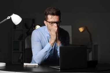 Stresli genç adam akşam geç saatlerde işyerinde