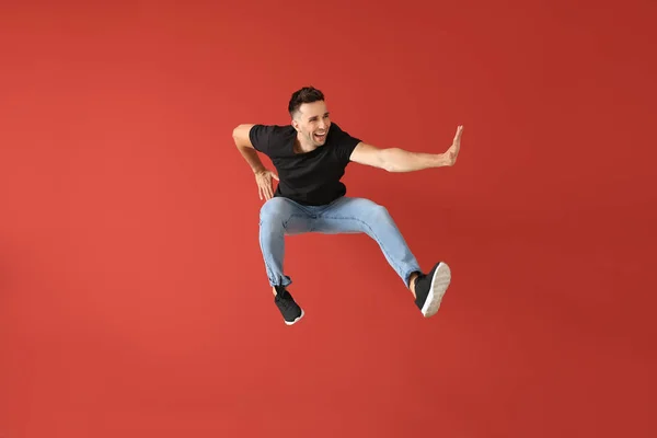 Handsome jumping young man against color background — Stock Photo, Image