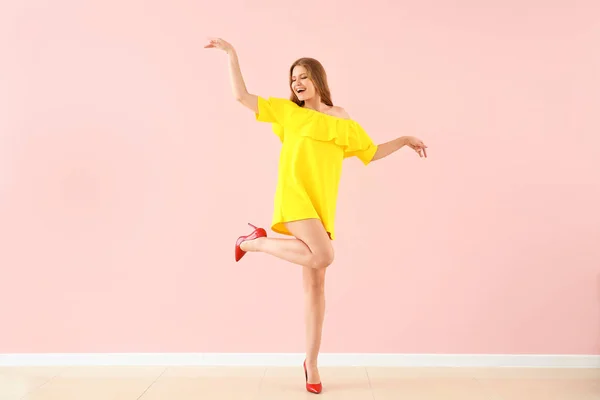 Beautiful young woman dancing against color wall — Stock Photo, Image