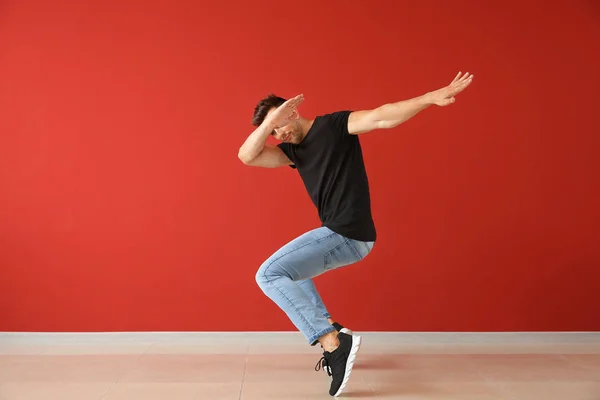 Beau jeune homme dansant contre le mur de couleur — Photo