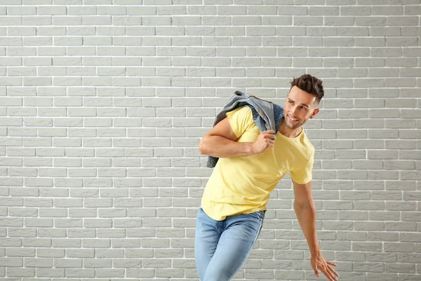 Handsome young man dancing against brick wall — Stock Photo, Image
