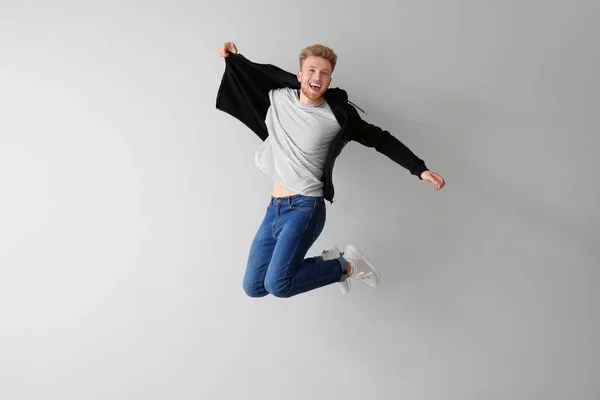 Bonito jovem pulando contra fundo claro — Fotografia de Stock