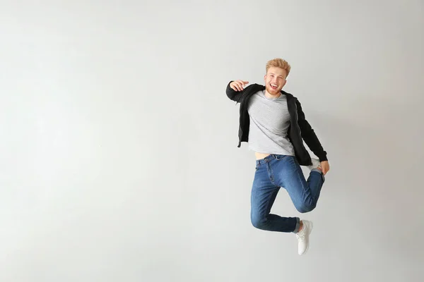 Handsome jumping young man against light background — Stock Photo, Image