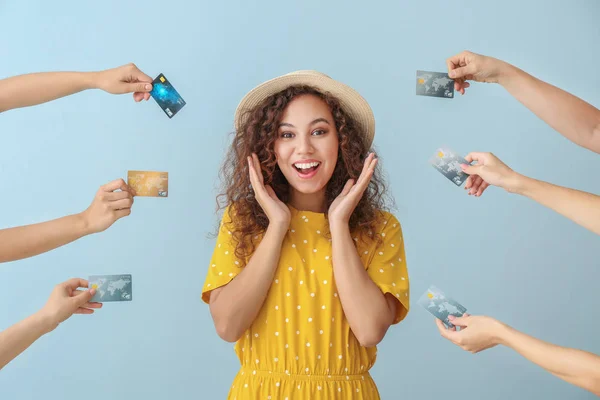 Jonge Afro-Amerikaanse vrouw en handen met creditcards op kleur achtergrond — Stockfoto