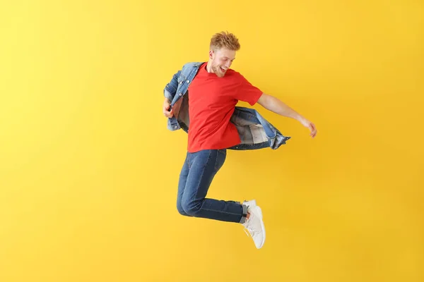 Handsome jumping young man against color background — Stock Photo, Image