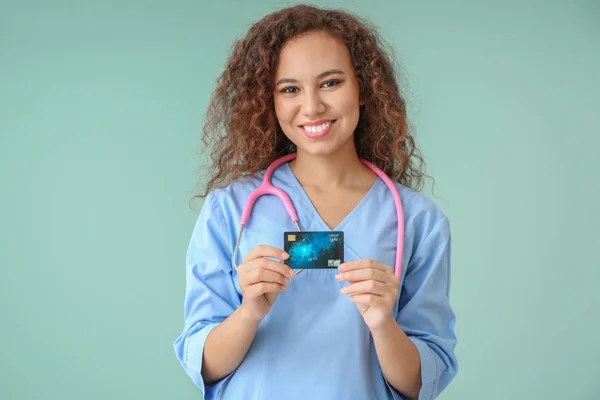 Afro-amerikai orvos bankkártyával, színes háttérrel — Stock Fotó