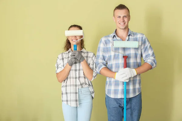 Feliz pareja joven con rodillos de pintura durante la reparación de su nueva casa — Foto de Stock