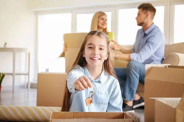 Happy girl with keys and her parents in new home — Stock Photo, Image