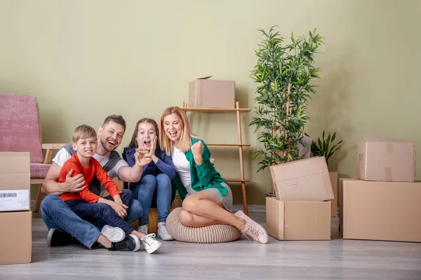 Família feliz com pertences e chaves em sua nova casa — Fotografia de Stock